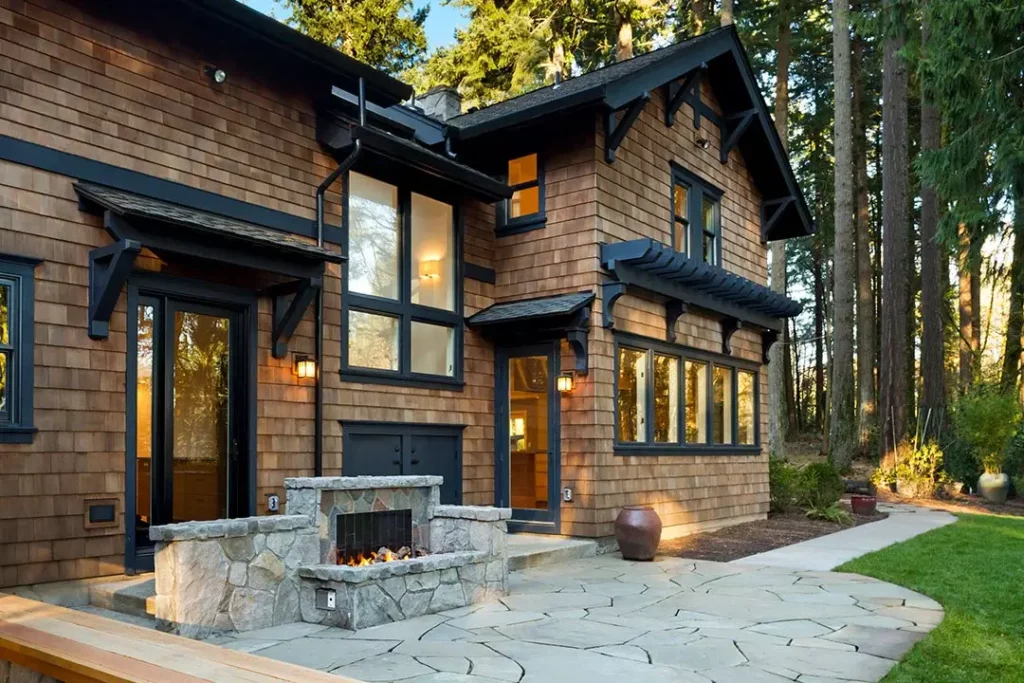 A wood-sided house with black trim and a stone outdoor living space.
