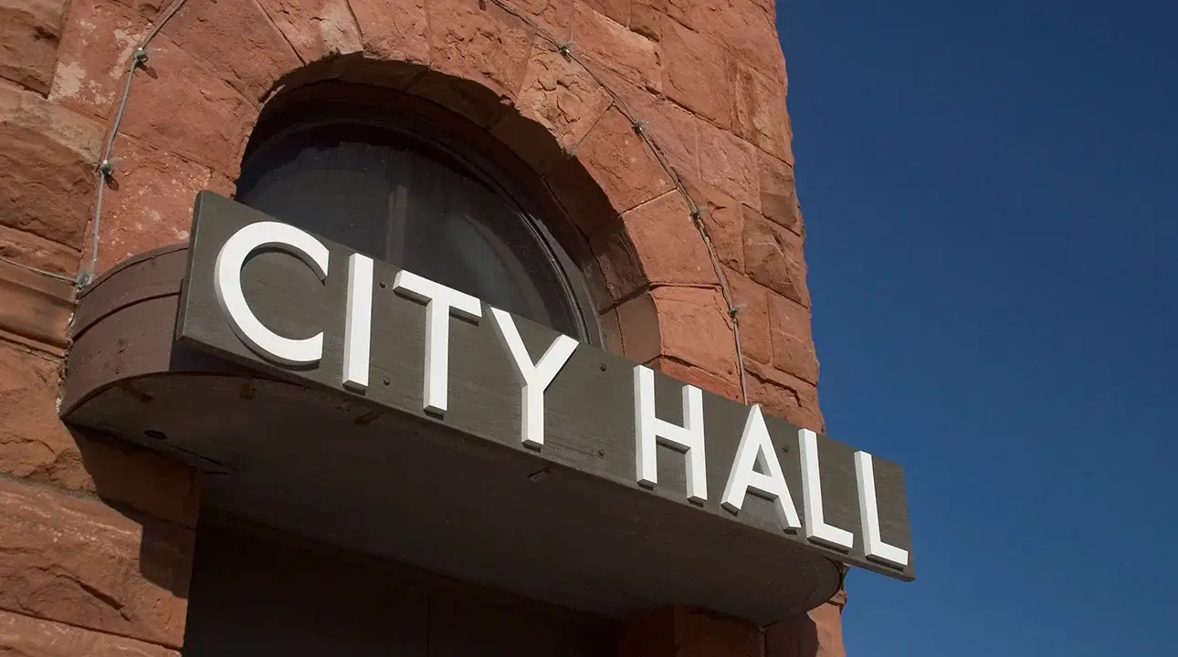 A sign that says City Hall on a large brick building.