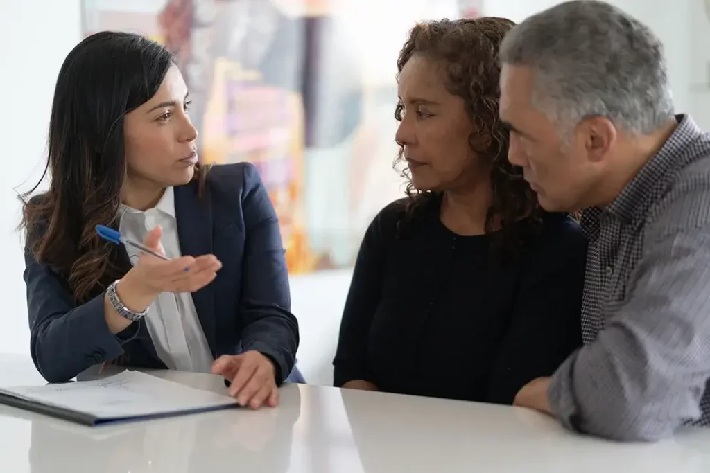 A couple and businessperson holding a pen with paper on the table having a serious discussion.